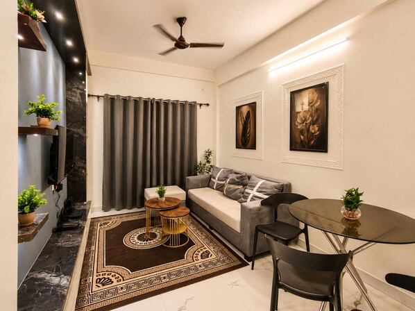 A modern living room with a sofa, a coffee table, a TV mounted on the wall, and a ceiling fan.