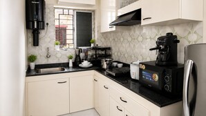 A kitchen with white cabinets, a black countertop, a coffee maker, and a stainless steel refrigerator.