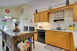 A kitchen with wooden cabinets, a dishwasher, and a dining area with a table and chairs. - Hot Tub & Deck! Loganville Group Retreat (Loganville)