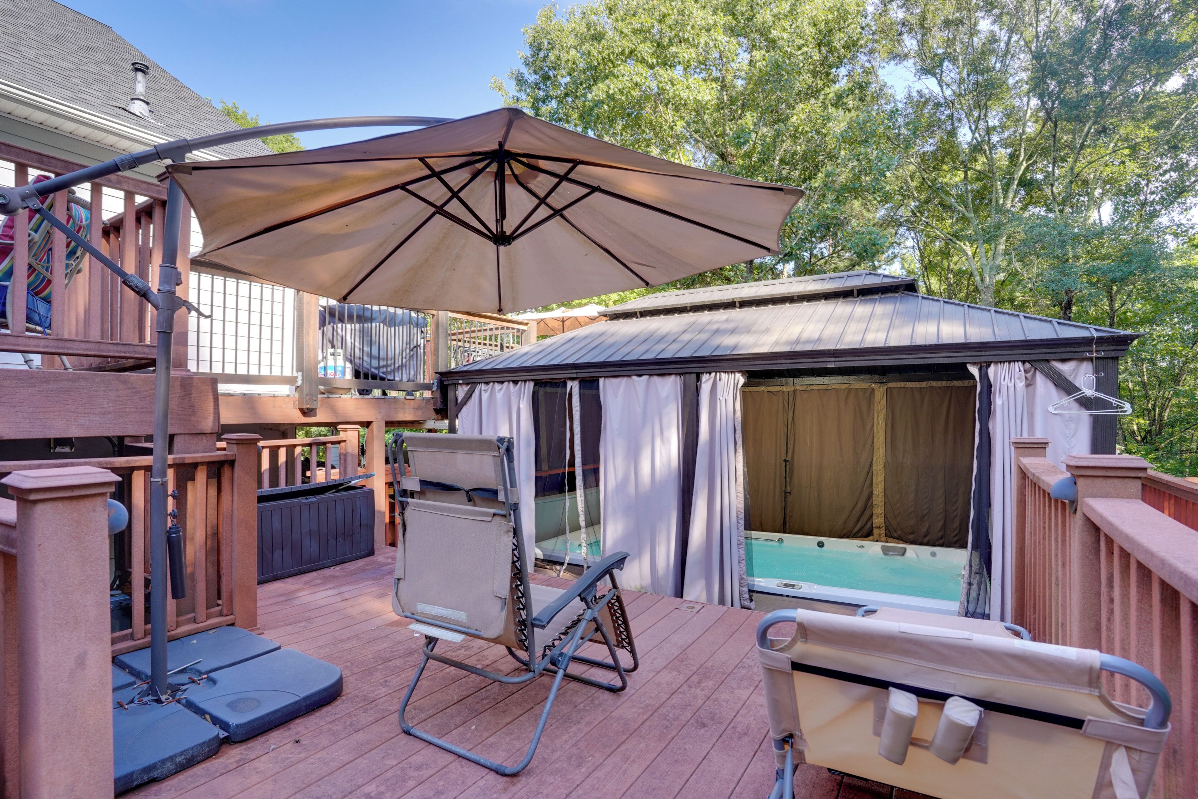 Eine Terrasse mit Whirlpool, überdachter Sitzgelegenheit und Pool.