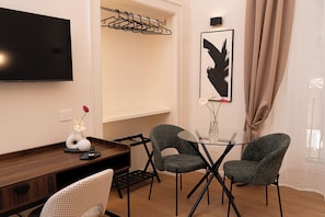 A modern room with a flat-screen TV, a dining table with chairs, a coat rack, and a framed artwork on the wall. - Tempora Domus E' (Naples)