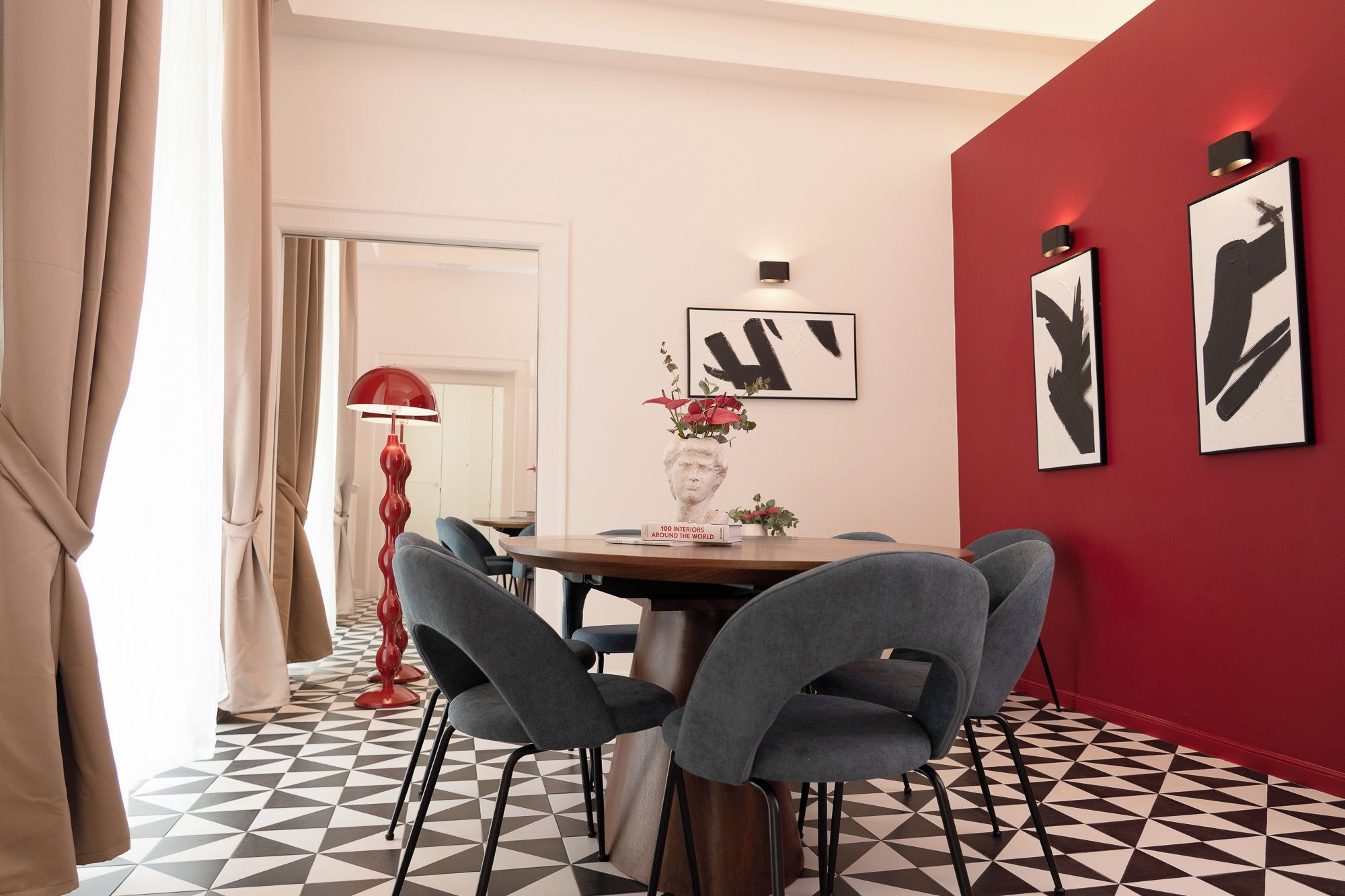 Comedor con pared roja, piso de estampado blanco y negro y mobiliario moderno.