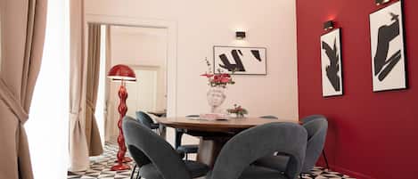 Comedor con pared roja, piso de estampado blanco y negro y mobiliario moderno.