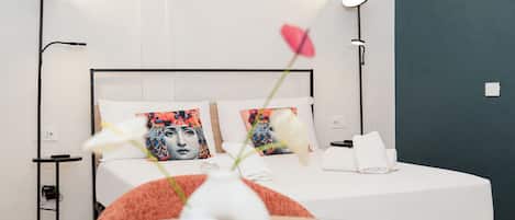 Una habitación de hotel moderna con cama, lámparas de noche, un florero con flores y un aplique de pared.