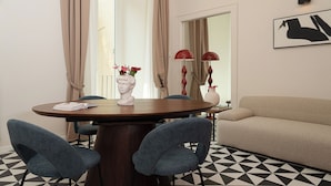 A dining area with a round table, two chairs, a vase with flowers, and a sofa. - Tempora Domus E' (Naples)