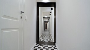 A hallway with a checkered floor pattern, white walls, and a door on the left. - Tempora Domus E' (Naples)
