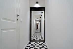 A hallway with a checkered floor pattern, white walls, and a door on the left. - Tempora Domus E' (Naples)