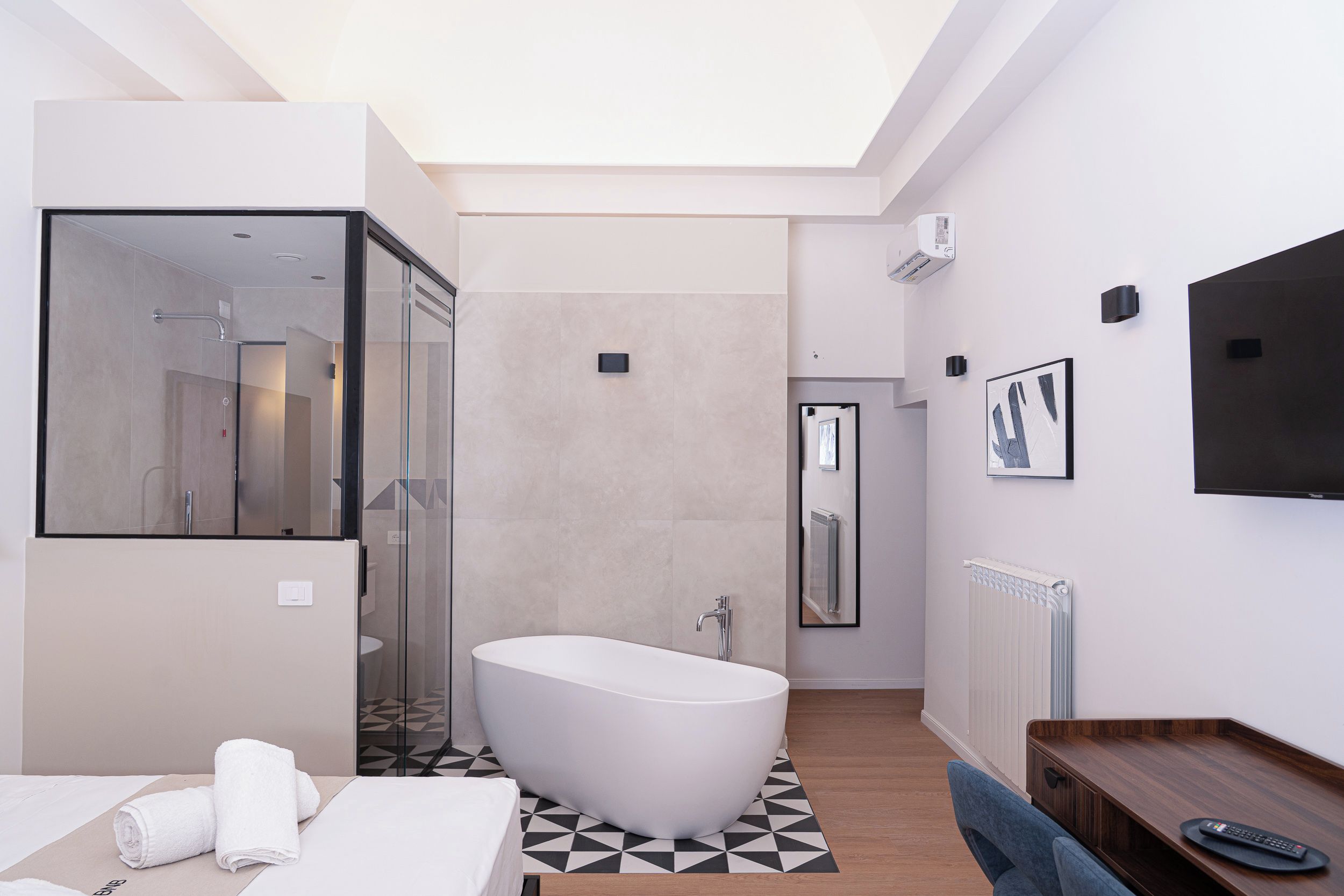 Un baño moderno con una bañera independiente, cabina de ducha con mampara de vidrio y un espejo grande.