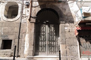 A building facade with a metal gate, a small window, and a door with a fanlight. - Tempora Domus E' (Naples)