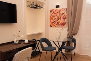 A modern room with a TV, a painting, a dining table with chairs, and a vase with flowers. - Tempora Domus E' (Naples)
