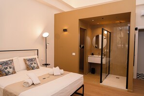 A hotel room with a bed, bedside lamp, and a bathroom with a shower and sink. - Tempora Domus E' (Naples)