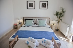 Ein ordentlich eingerichtetes Hotelzimmer mit einem Bett, Nachttischlampen, einer Zimmerpflanze und einem Heizkörper.