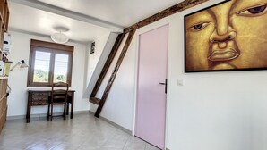 Een kamer met een bureau, stoel en een groot schilderij aan de muur.