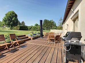 A wooden deck with outdoor furniture, a barbecue grill, and a garden area with a swing set. - Family-friendly country cottage near the Forêt d'Orient Natural Park, (Jasseines)