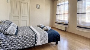 Een slaapkamer met een bed, een kast, een radiator en een raam met gordijnen.