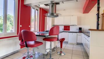A kitchen with red chairs, a coffee machine, and a view of greenery outside.