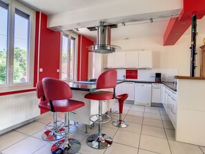 A kitchen with red chairs, a coffee machine, and a view of greenery outside. - Family-friendly country cottage near the Forêt d'Orient Natural Park, (Jasseines)