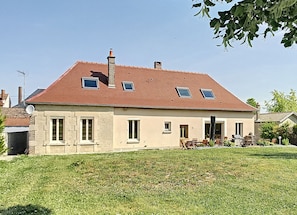 A two-story house with a sloped roof, multiple windows, and a visible chimney.