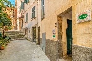 A narrow street with buildings on either side, a sign for 'AFFIETTACAMERE' indicating a guest room, and a small staircase leading to the entrance. - [ARio] Riomaggiore-5TERRE-A/C-best position (Riomaggiore)