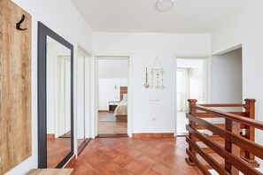 Ein Flur mit Holzboden und Holzwand, am Ende ist ein Bett zu sehen.