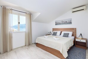 Ein Schlafzimmer mit einem Bett, einem Nachttisch, einem Fenster mit Vorhängen und einem Bild an der Wand.