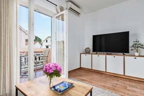 Ein modernes Wohnzimmer mit Flachbildfernseher, einem Holztisch mit einem Buch und einer Topfpflanze.