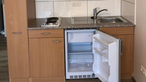 A compact kitchen with a microwave, sink, and a built-in refrigerator.