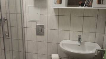 Ein Badezimmer mit Toilette, Waschbecken, Dusche und Spiegel.