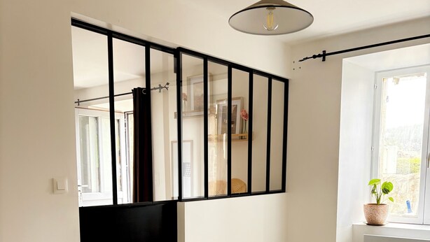 Ein Schlafzimmer mit einem Bett, einem Fenster, einer Heizung und einer Pendelleuchte.
