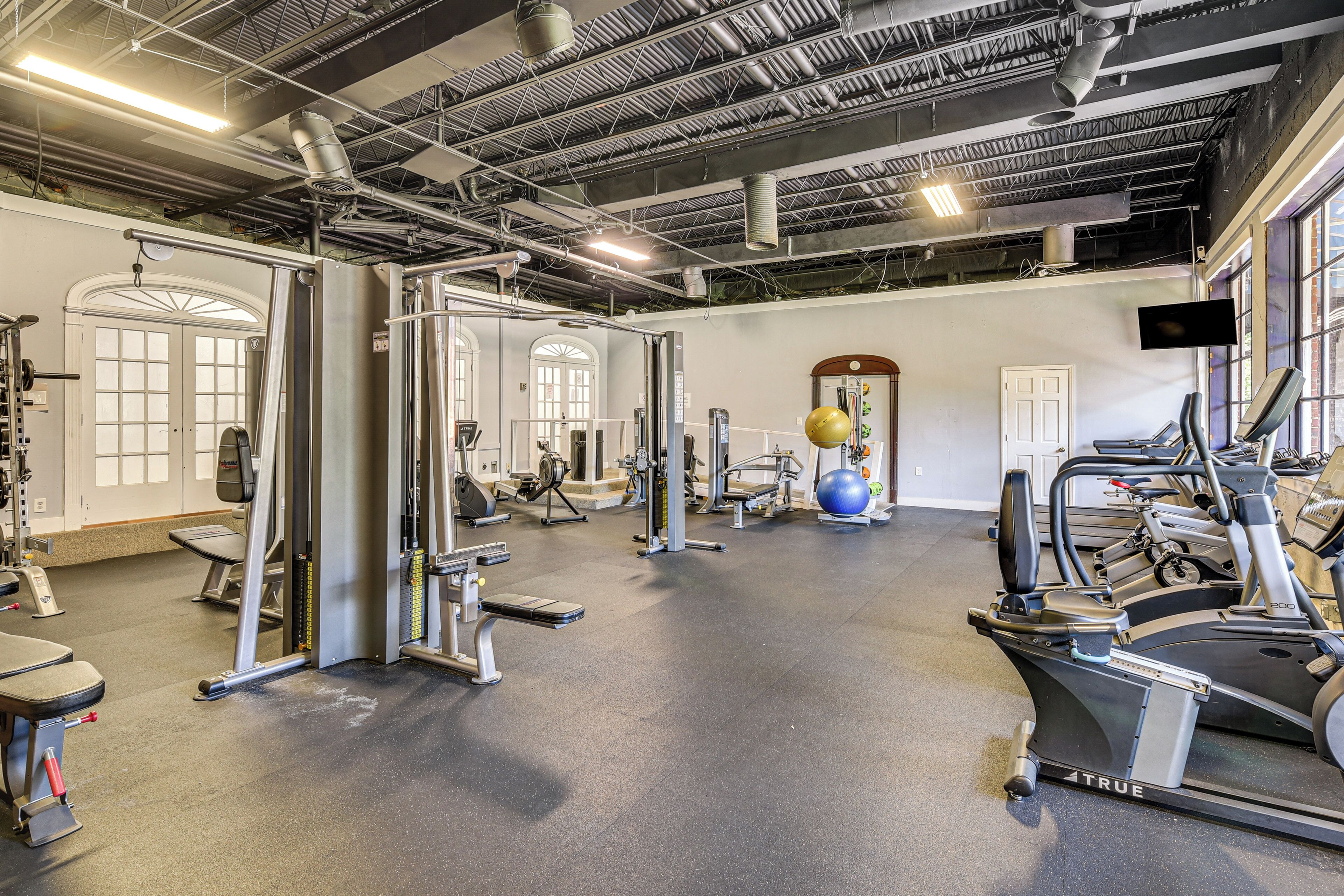 Ett gym med olika typer av träningsutrustning, inklusive löpband och styrketräningsmaskiner.