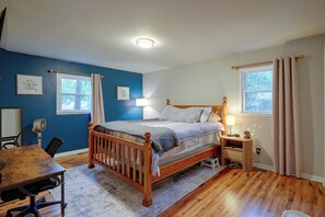 A bedroom with a wooden bed, bedside lamps, a desk, and a chair. - Fire Pit & Grill! Wooded Durham Retreat (Durham)