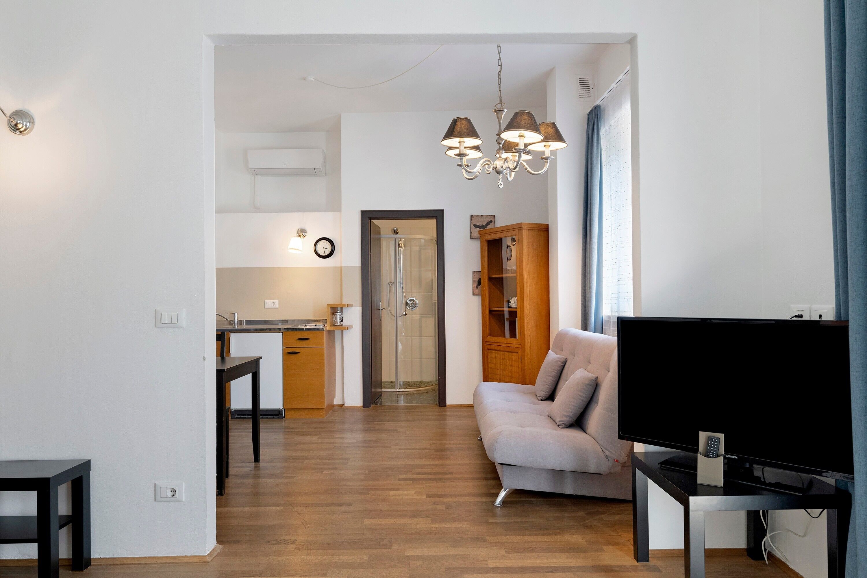 Una sala de estar moderna con un televisor de pantalla plana, un sofá y un comedor con una mesa y sillas.