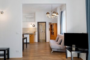 Ein modernes Wohnzimmer mit Flachbildfernseher, einer Couch und einem Essbereich mit Tisch und Stühlen.