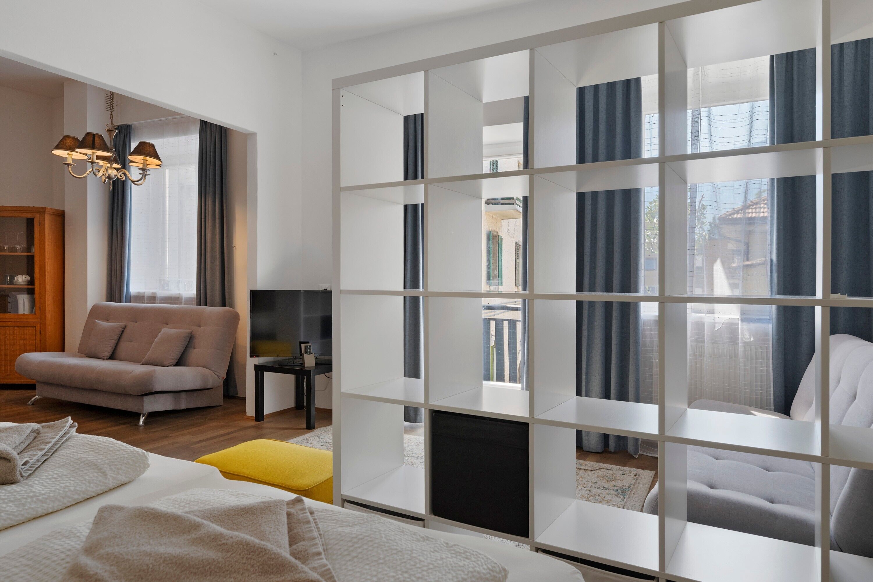 Una sala de estar moderna con sofá, mesa de centro, televisor y una lámpara decorativa.