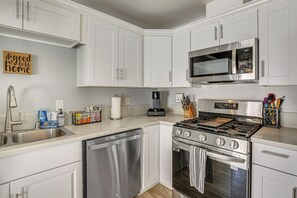 A modern kitchen with white cabinets, stainless steel appliances, and a coffee maker.