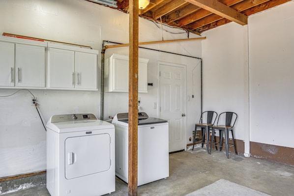 A laundry room with two white washing machines, a wooden beam ceiling, and a white door.