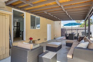 Une terrasse extérieure avec des meubles en osier, un plafond couvert et une vue sur le jardin arrière.