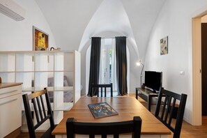 Un'area pranzo con un tavolo di legno, sedie nere, una libreria, una televisione e opere d'arte alle pareti.