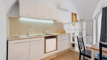 Une cuisine moderne avec des meubles blancs, un four encastré et une table à manger en bois, assortie de chaises.