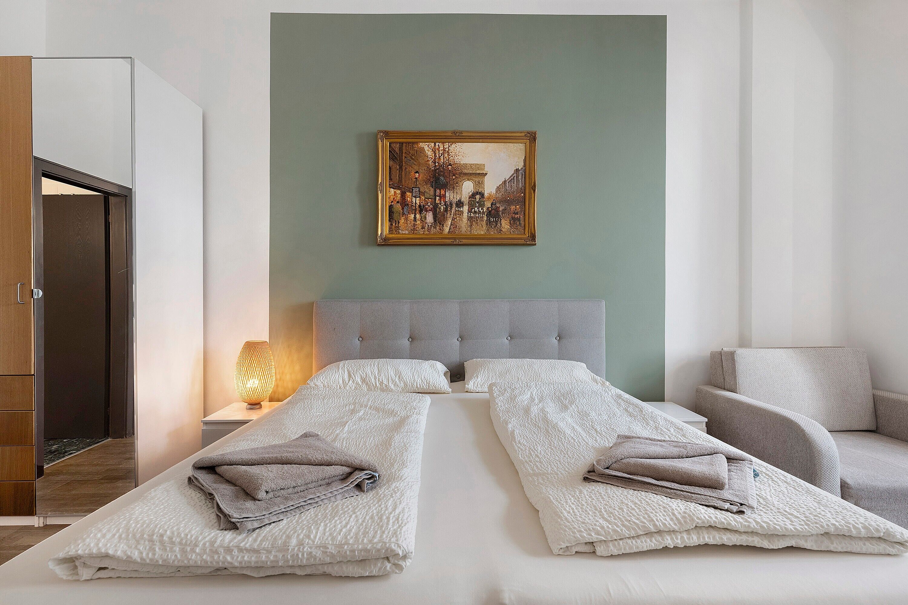 Una habitació d'hotel amb un llit, un quadre, una tauleta de nit i una làmpada.