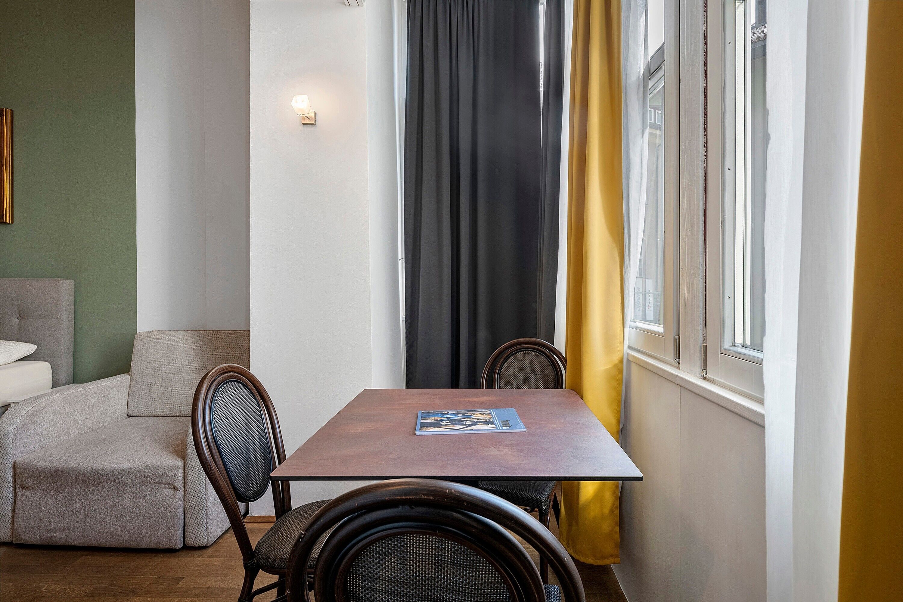 Un comedor con mesa, sillas, sofá y una ventana con cortinas.
