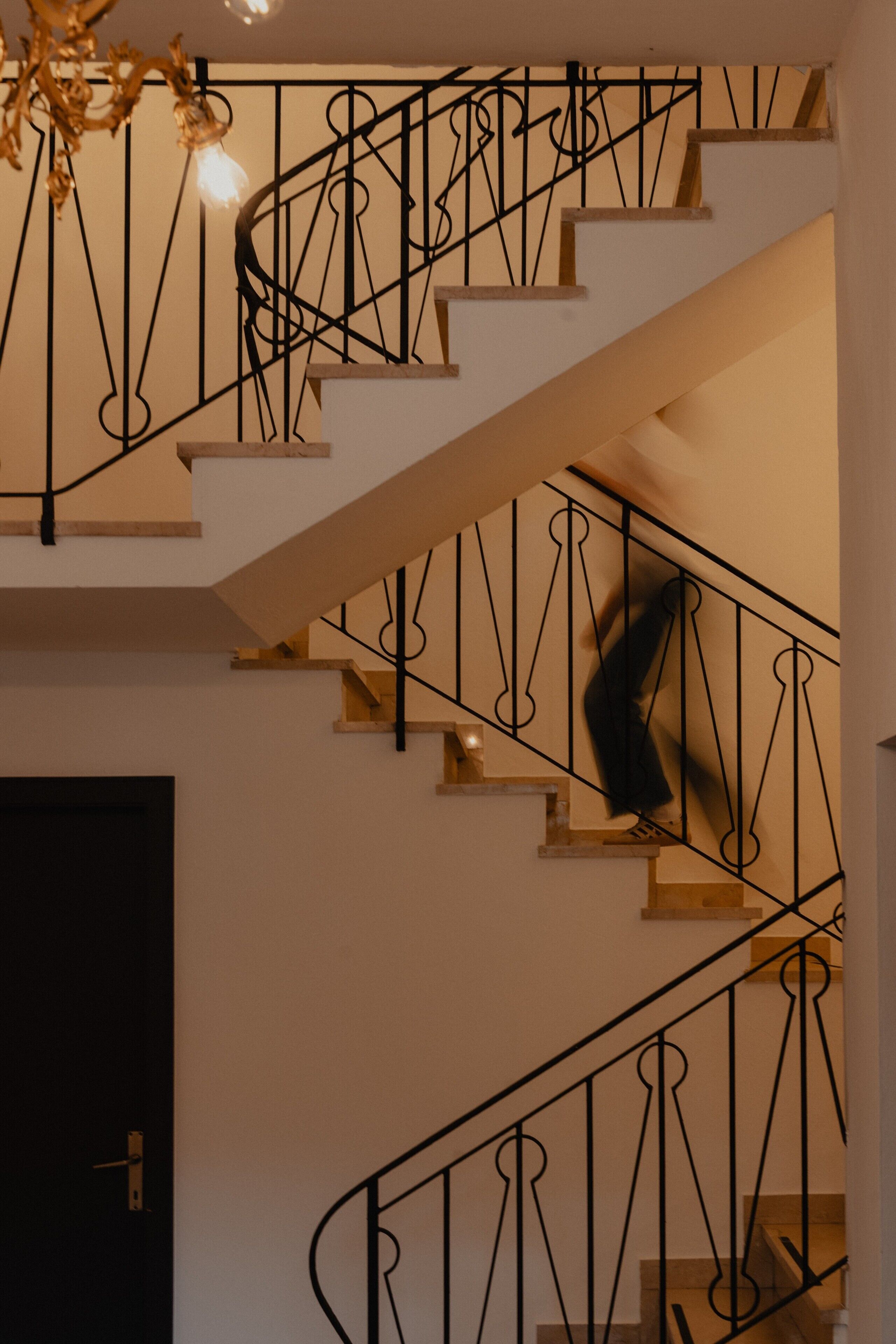 A staircase with ornate metal railings and a chandelier.