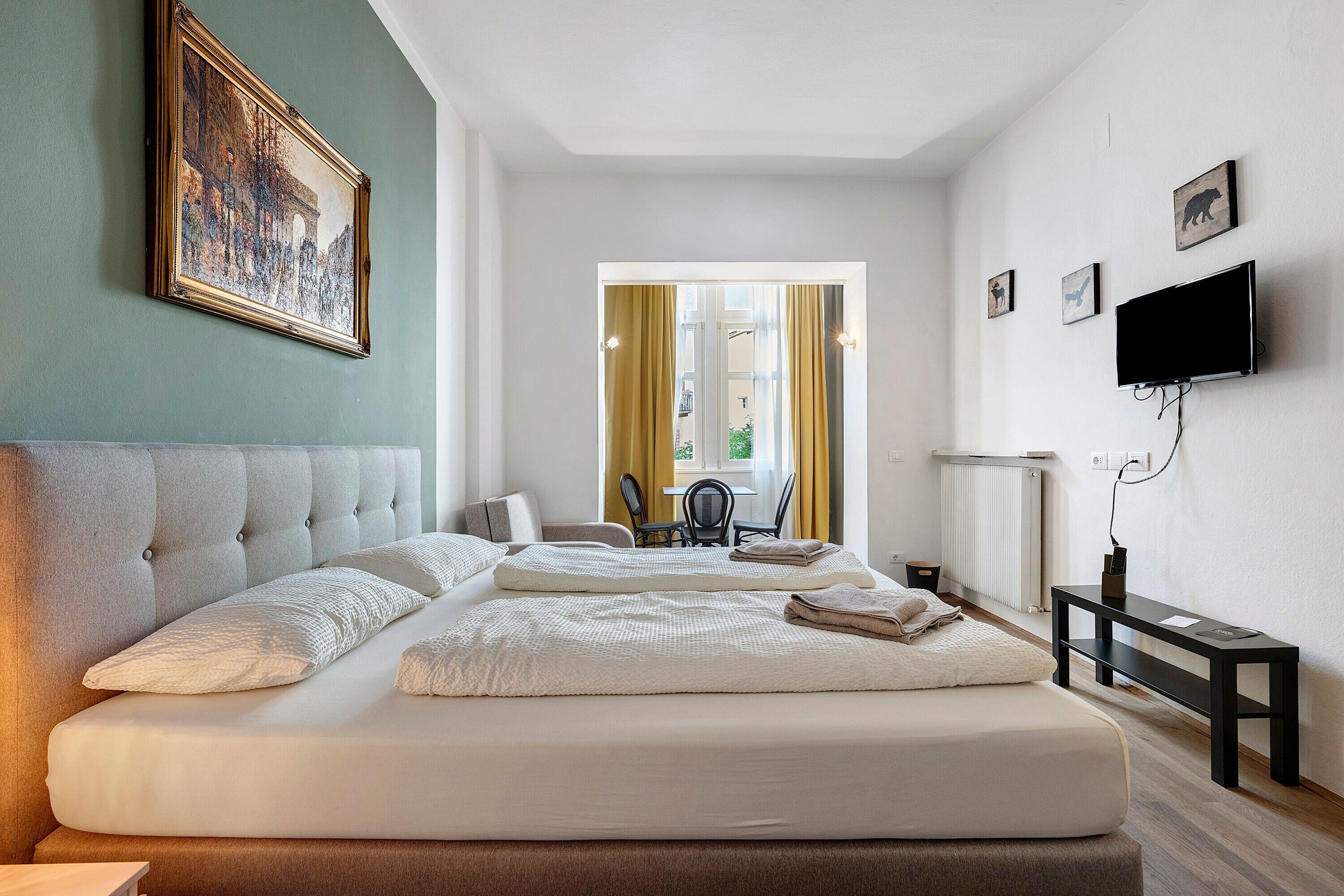 Una habitación de hotel con una cama grande, televisión y un cuadro en la pared.