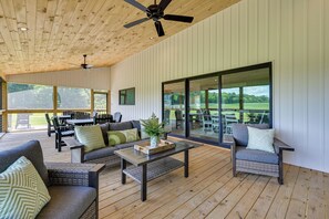 Un espace de vie à aire ouverte doté d’un ventilateur de plafond, de grandes fenêtres et d’un coin salon extérieur.