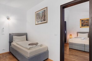 A bedroom with a bed, a bedside table, a wall-mounted light, and a framed picture.