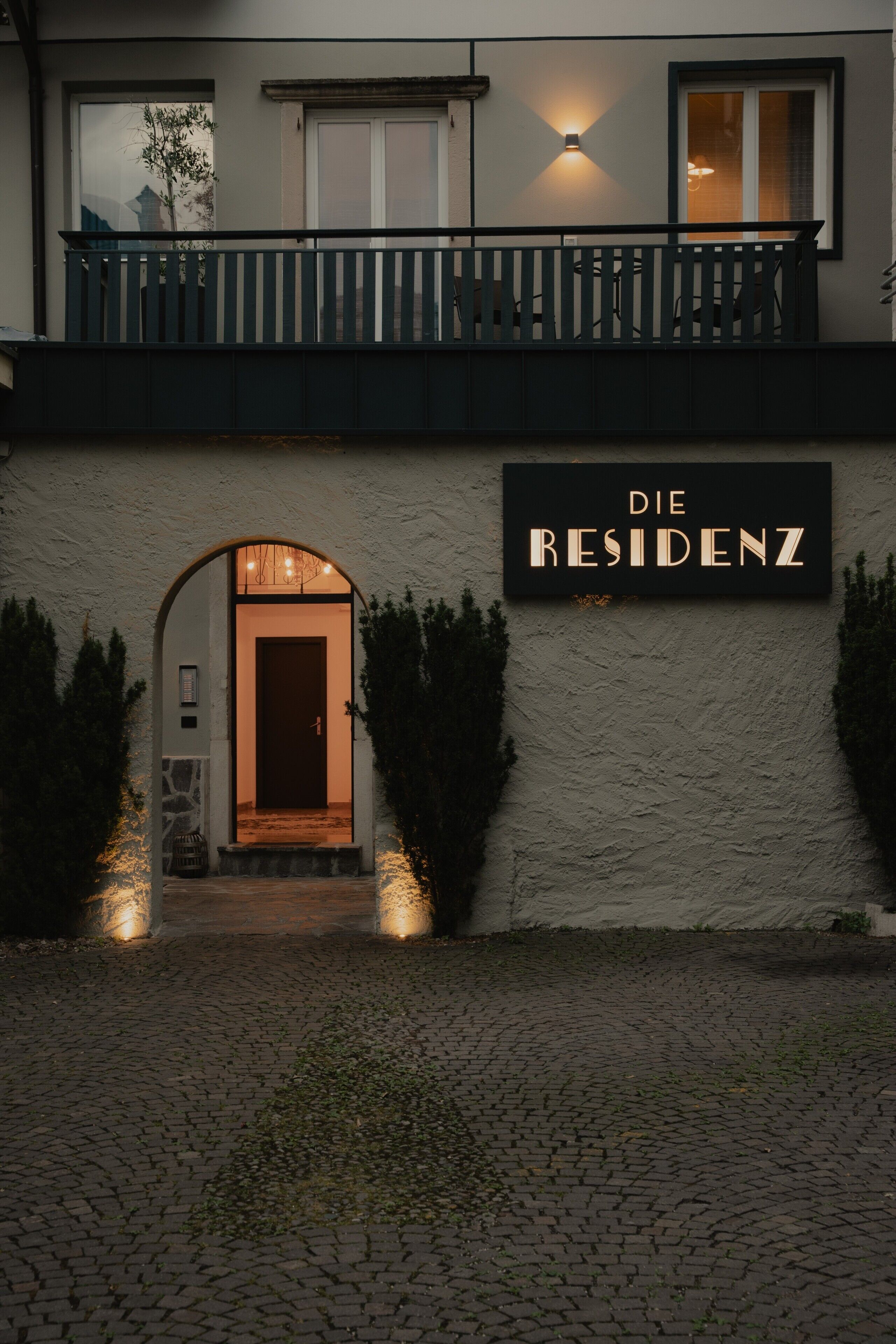 Un edificio con un cartello che riporta 'Die RESIDENZ' e un balcone.