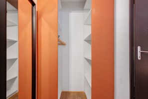 A narrow hallway with orange walls and white shelving units.