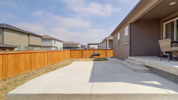 A residential backyard with a concrete patio, a wooden fence, and a barbecue grill. - Private Yard w/ Patio! Modern Commerce City Gem (Commerce City)