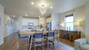 A spacious kitchen with modern appliances, a dining area with wooden chairs, and a cozy seating area with a sofa. - Private Yard w/ Patio! Modern Commerce City Gem (Commerce City)