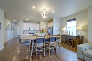 A spacious kitchen with modern appliances, a dining area with wooden chairs, and a cozy seating area with a sofa. - Private Yard w/ Patio! Modern Commerce City Gem (Commerce City)